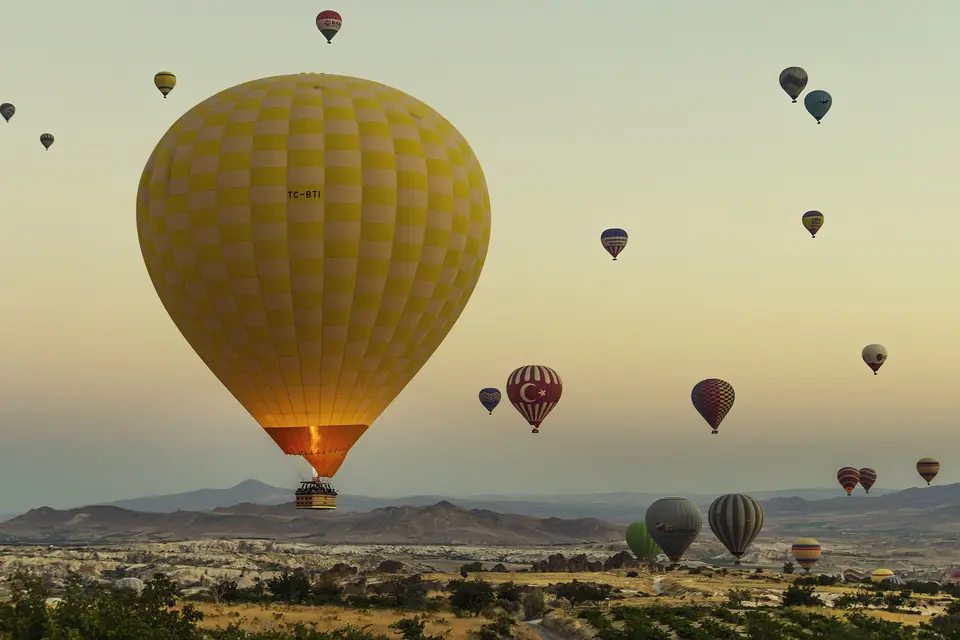 Hot-air balloons rising over Cappadocia in golden sunrise light