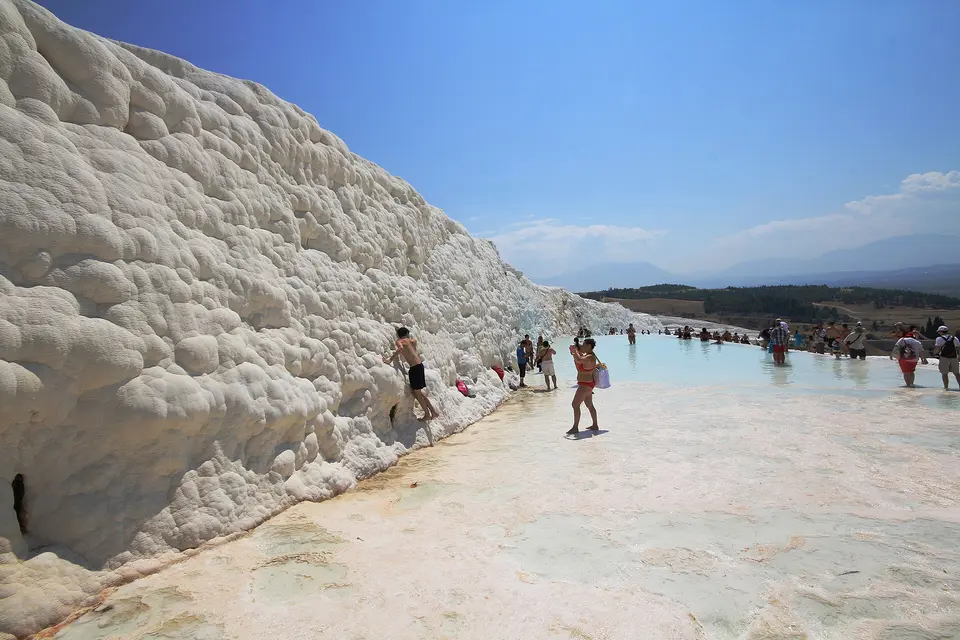 Visitors walking barefoot through the shallow pools of the Pamukkale terraces